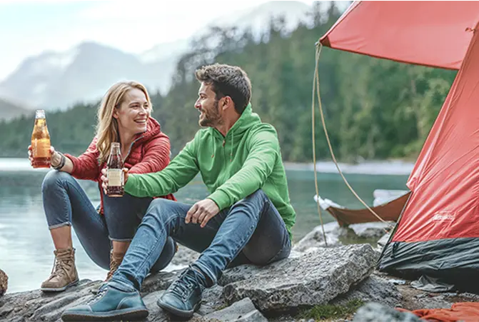 Personen sitzen vor dem Campingzelt.
