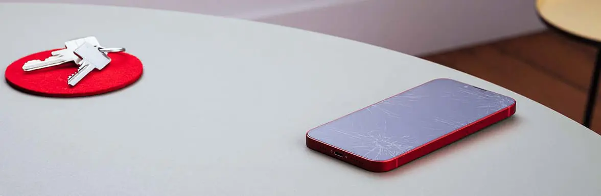 Auf dem Tisch liegt ein Handy mit gerochenem Display.