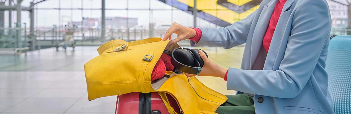 Person packt Bluetooth-Kopfhörer in das Handgepäck.