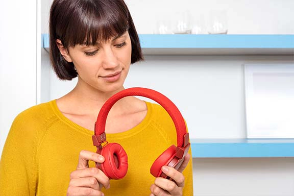Person hat On-Ear-Bluetooth-Kopfhörer in der Hand und schaut auf die Polster der Kopfhörer.