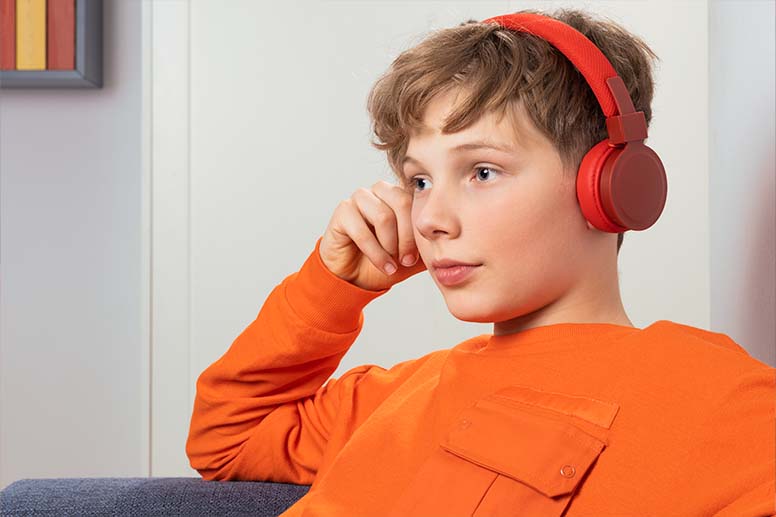 Jugendlicher hört zuhause Musik über On-Ear-Kopfhörer.