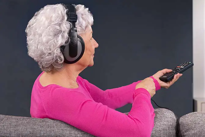 Person schaut mit Kopfhörern Fernsehen.