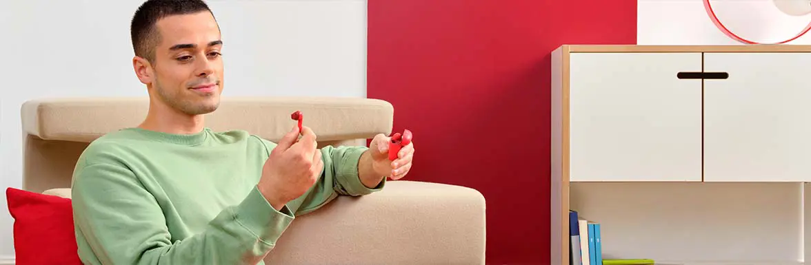 Person mit True Wireless-Kopfhörern in der Hand.