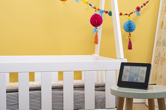 Smarte Wetterstation steht auf einem Nachttisch neben dem Babybett