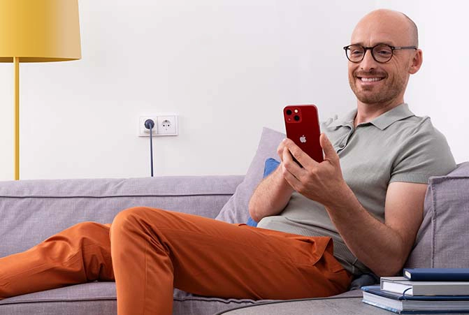 Person sitzt mit Smartphone auf dem Sofa.