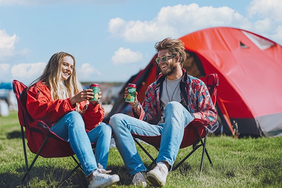 Zwei Freunde sitzen auf Liegestühlen auf dem Campingplatz des Festivals.