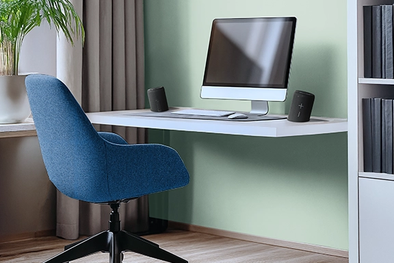 Auf einem Schreibtisch steht der True-Wireless-Stereo-Lautsprecher geteilt jeweils links und rechts neben dem PC.