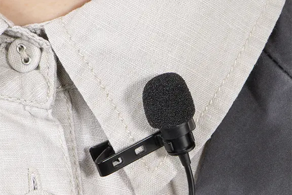 Ansteckmikrofon ist am Hemdkragen festgeclippt.